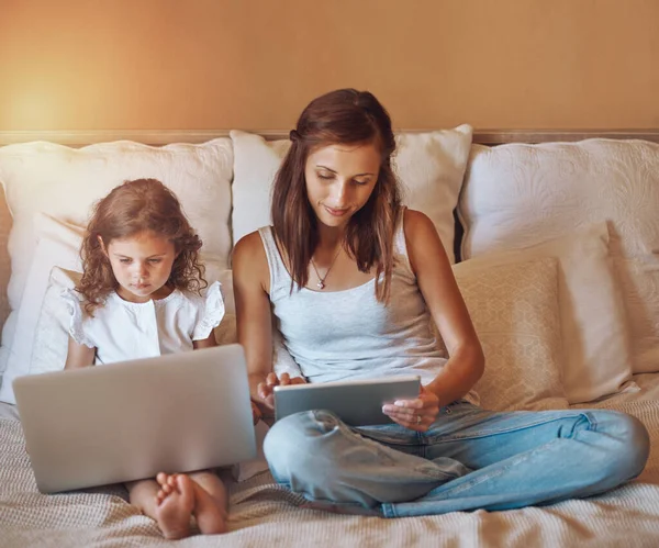 Relaksują się swoimi gadżetami. Zdjęcie dziewczynki korzystającej z laptopa i jej matki korzystającej z tabletu cyfrowego w domu. — Zdjęcie stockowe