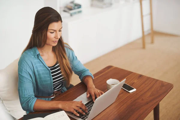 Arbetar hemifrån. Skjuten av en fokuserad frilansare som använder sin bärbara dator när hon arbetar hemifrån. — Stockfoto