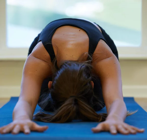 Yoga får mig til at føle mig mere nærværende. Et billede af en ung kvinde, der praktiserer yoga derhjemme. - Stock-foto