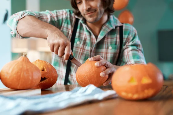 I carve the best pumpkins. Shot of a young man carving a pumpkin at home.