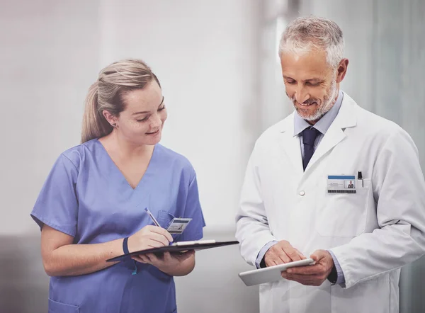 Son dossier médical a été numérisé. Plan recadré de deux médecins en train de discuter dans un hôpital. — Photo