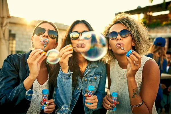 Ни один момент, потраченный на выдувание пузырей, не был потрачен впустую. Снято группой молодых женщин, пускающих пузыри вместе на открытом воздухе. — стоковое фото