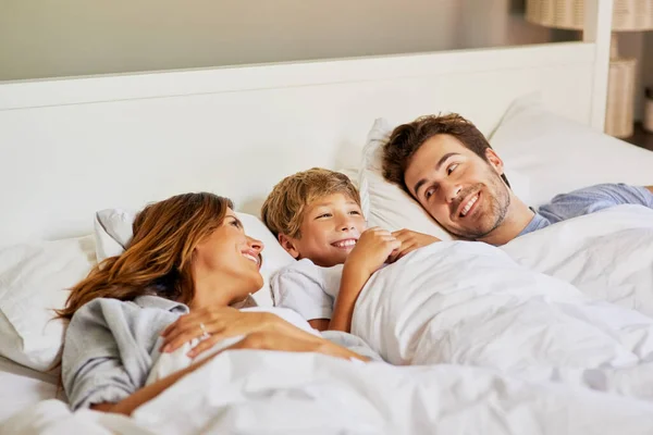 Делаю утреннее семейное время. Съемка веселой молодой семьи, отдыхающей в постели дома в течение дня. — стоковое фото