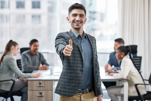 Podemos lograr cualquier cosa como equipo. Fotografía de un joven empresario mostrando un pulgar hacia arriba mientras estaba en una reunión en el trabajo. — Foto de Stock