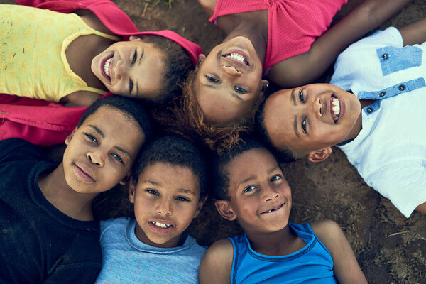 Kids will be kids. High angle portrait of children lying on the grass together outside.