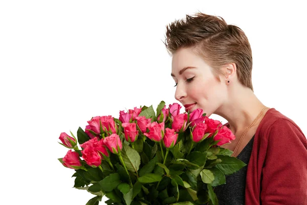 Stanna och lukta på rosorna. Studio skott av en ung kvinna luktar en bukett blommor mot en vit bakgrund. — Stockfoto