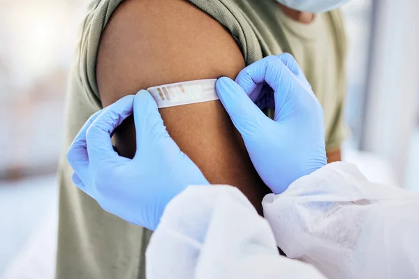 Wszystko załatwione. Przycięte ujęcie nierozpoznawalnego lekarza umieszczającego plaster w miejscu wstrzyknięcia pacjenta po podaniu szczepionki zawierającej żylaki 19. — Zdjęcie stockowe