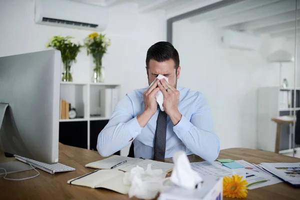 Geen ziektedagen meer. Schot van een jonge zakenman met allergieën op het werk. — Stockfoto