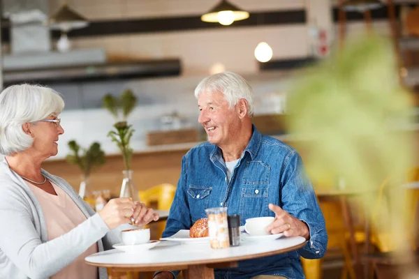 Dohání mě nad hrnkem. Snímek šťastného staršího páru relaxaci s šálkem kávy v kavárně. — Stock fotografie
