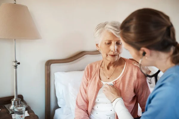 Eens kijken wat je hart te zeggen heeft. Schot van een oudere vrouw krijgt een check-up van een jonge verpleegster in een bejaardentehuis. — Stockfoto