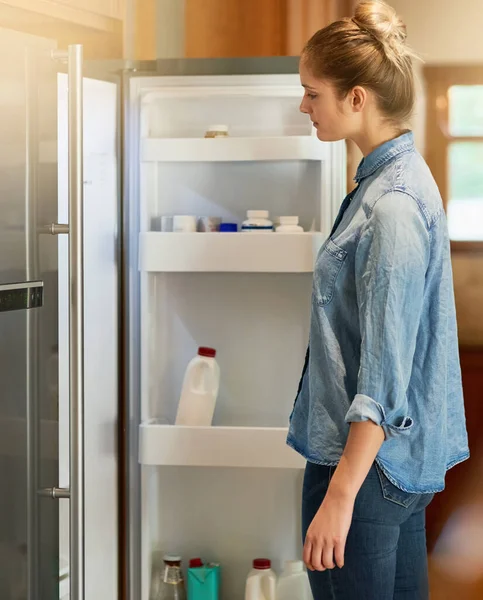 Cuando el hambre golpea.... Recortado tiro de una mujer joven mirando dentro de su refrigerador en casa. — Foto de Stock