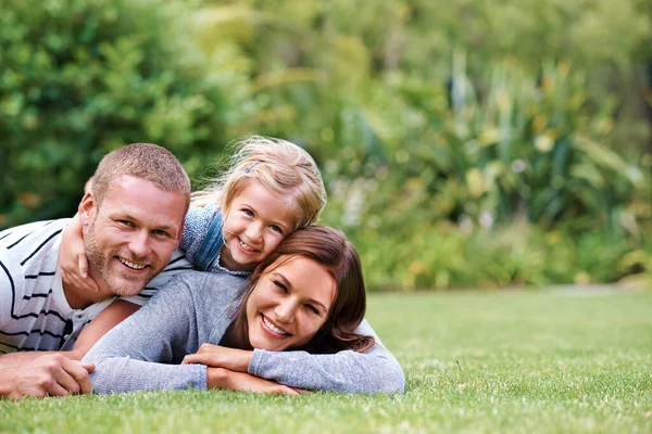 Užívat si to s mámou a tátou. Portrét šťastné trojčlenné rodiny ležící venku na trávě. — Stock fotografie