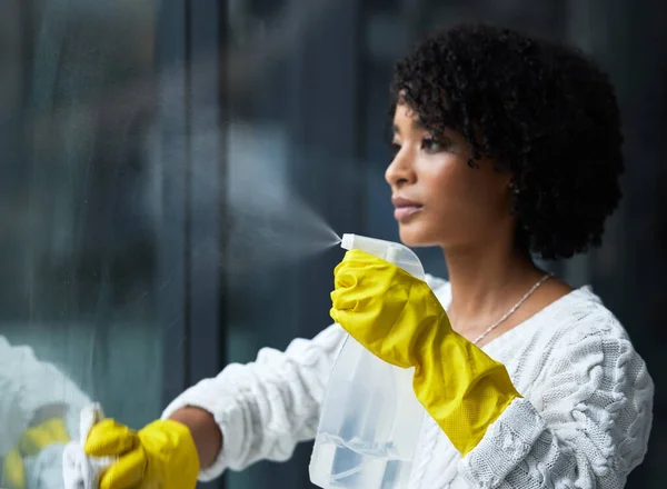 Ik denk dat het tijd is om mijn ramen schoon te maken. Schot van een jonge vrouw die haar ramen schoonmaakt. — Stockfoto
