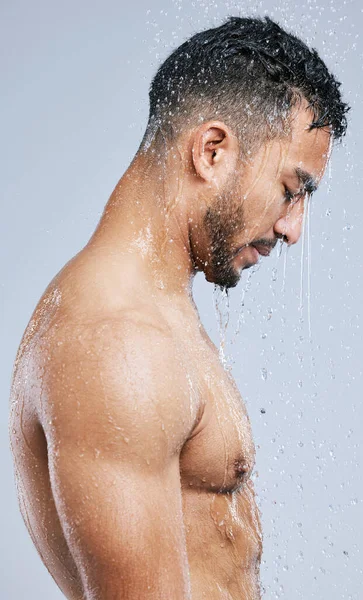 La douche est le meilleur endroit pour se perdre dans vos pensées. Plan studio d'un beau jeune homme prenant une douche sur fond gris. — Photo