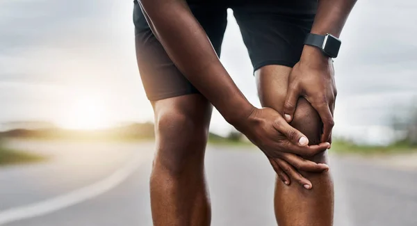 Dit voelt niet goed. Close-up shot van een sportieve man die last heeft van kniepijn tijdens het sporten buiten. — Stockfoto