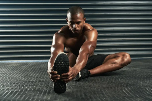 Lekker warm voor z 'n training. Full length shot van een atletische jongeman gaat door zijn warming-up routine in de studio. — Stockfoto