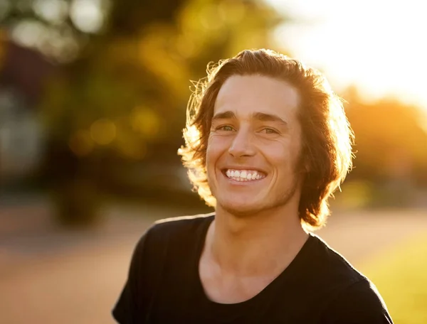 夏はいつも笑顔になる。太陽の下で立っているハンサムな若い男の肖像画. — ストック写真