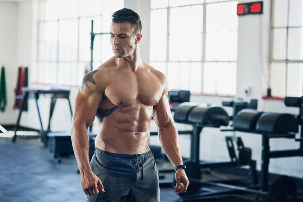 Manténgase fuerte, entrenamiento para llegar a ser aún más fuerte. Foto de un joven guapo haciendo ejercicio en el gimnasio. — Foto de Stock