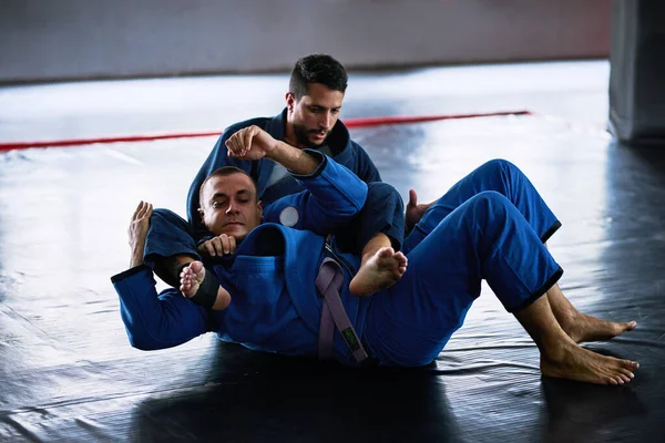 Ta den till mattan. Full längd skott av två unga manliga idrottare sparring på golvet i sin dojo. — Stockfoto