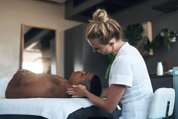 Dit is jouw traktatie, geniet ervan. Shot van een jonge man het krijgen van een gezicht massage in een spa. — Stockfoto