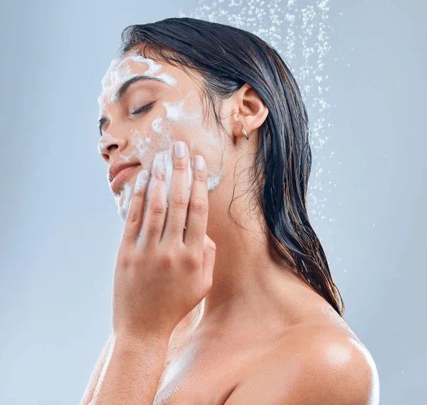 Ella tiene el secreto de la piel suave. Foto de una joven lavándose la cara en la ducha sobre un fondo gris. —  Fotos de Stock