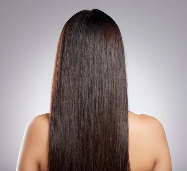 Egyszerűen sima szálak. Visszapillantás egy fiatal nő hosszú selymes haj pózol a szürke háttér. — Stock Fotó
