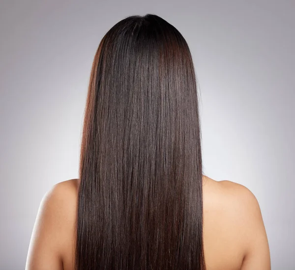 Gewoon gestroomlijnde strengen. Rearview shot van een jonge vrouw met lang zijdeachtig haar poseren tegen een grijze achtergrond. — Stockfoto