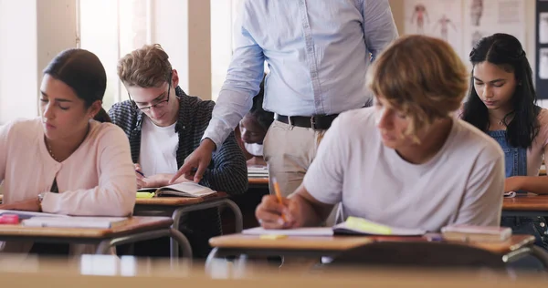 Maak van vandaag de dag dat je iets nieuws leert. Schot van tiener jongen vraagt zijn leraar om hulp tijdens een examen in een klaslokaal. — Stockfoto