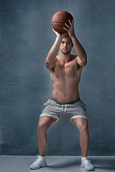 Som sa att fitness inte kan vara kul. Porträtt av en fokuserad ung man siktar innan du kastar en basket i studio. — Stockfoto