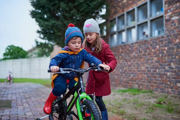 Je ne te laisserai pas tomber. Plan recadré d'une petite fille apprenant à son frère à faire du vélo à l'extérieur. — Photo