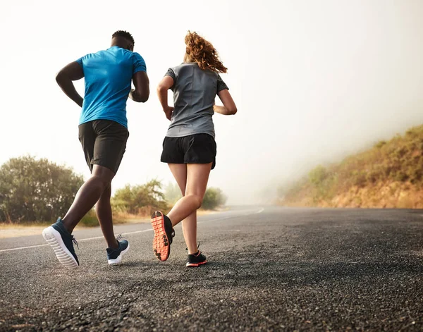 Blijf bij met hun fitness doelen. Achteraanzicht shot van twee sportieve jongeren uit voor een run samen. — Stockfoto