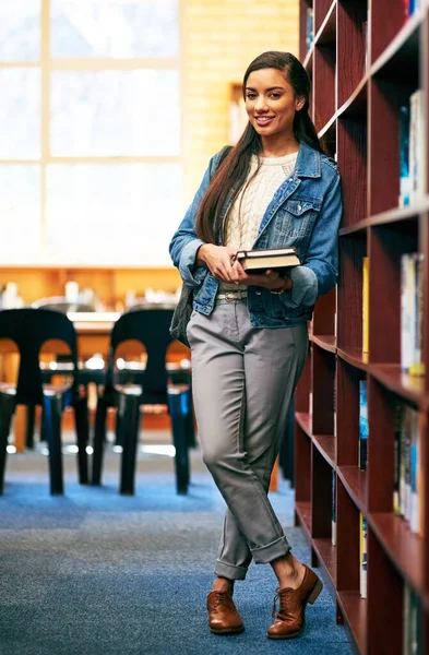 La biblioteca è un luogo per sperimentare una ricchezza di conoscenze. Ritratto di uno studente universitario in piedi nella biblioteca del campus. — Foto Stock