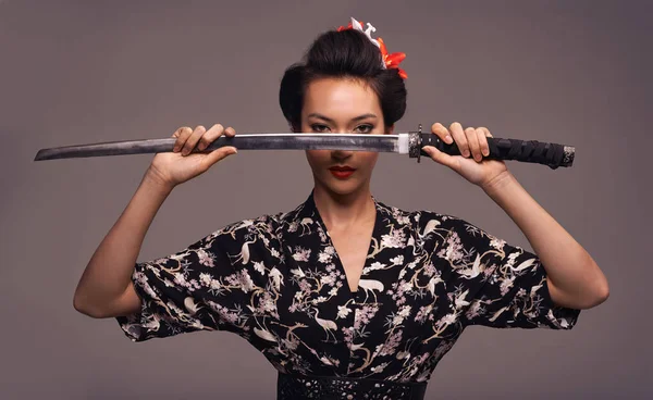 Biraz kılıç kullanma zamanı geldi. Samuray kılıcı tutan çekici genç bir kadının stüdyo fotoğrafı.. — Stok fotoğraf