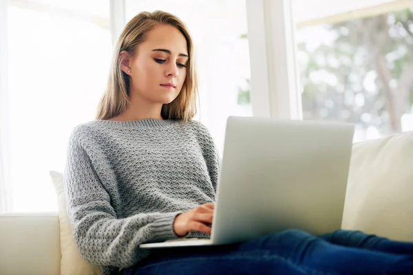Blogueando su nuevo hobby favorito. Recortado disparo de una atractiva joven mujer usando su computadora portátil mientras se enfría en casa. —  Fotos de Stock
