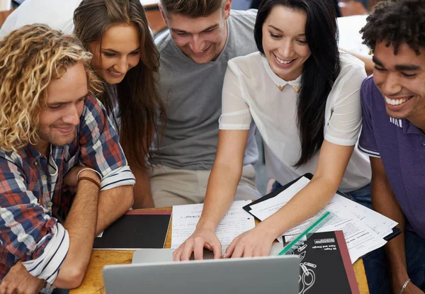 A rir entre as aulas. Tiro de um grupo de jovens estudantes universitários trabalhando juntos em um laptop. — Fotografia de Stock