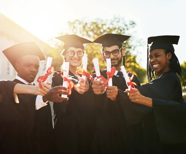 Acabamos de empezar. Fotografía de un grupo de estudiantes que mantienen juntos sus diplomas el día de la graduación. —  Fotos de Stock