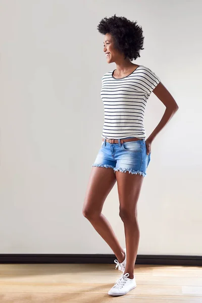 Le strisce sono ancora un fiocco di moda impressionante. Girato di una giovane donna attraente e felice che indossa un maglione a righe e pantaloncini di jeans all'interno. — Foto Stock