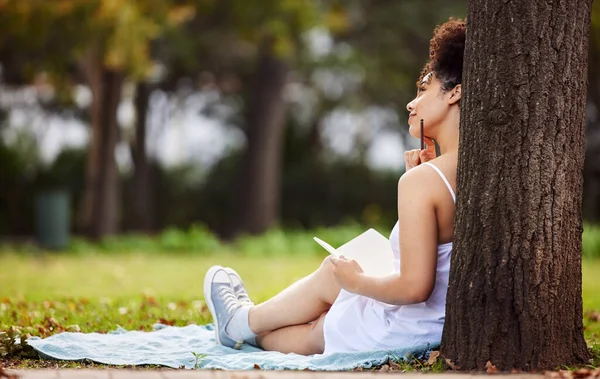 在想她的下一篇日记一个年轻貌美的女子坐在公园里写日记时的背景照片. — 图库照片