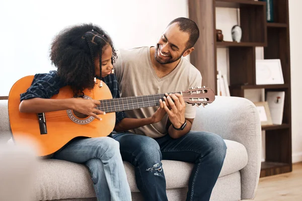 Pai, todas as filhas são fãs. Tiro de uma jovem aprendendo a tocar guitarra com seu pai em casa. — Fotografia de Stock