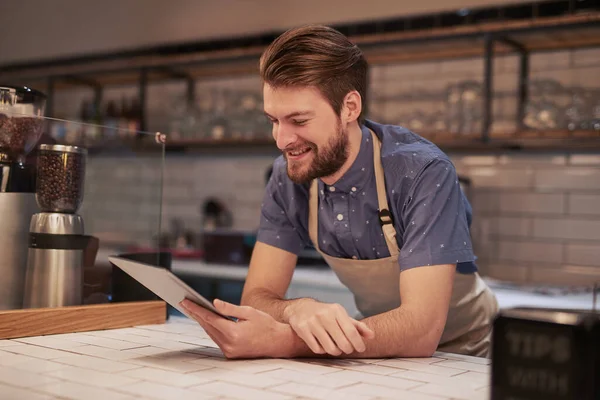 Creating inexpensive online advertisements to target local audiences. Shot of a young man using a digital tablet while working in a coffee shop. — Stock Photo, Image