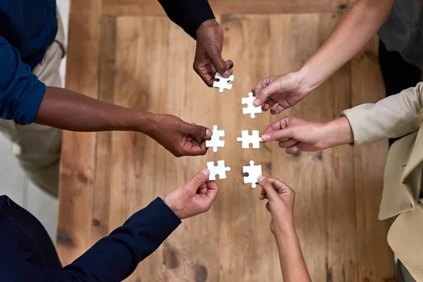 Non sono perplessi dal successo. Colpo ad angolo alto di un gruppo di uomini d'affari non identificabili che costruiscono un puzzle insieme in ufficio. — Foto Stock