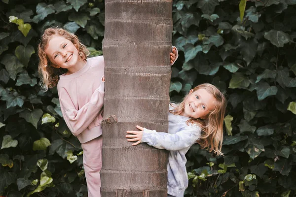 Adulthood can wait, we have a childhood to enjoy. Shot of two adorable little girls hugging a tree in a garden. — Stock Photo, Image