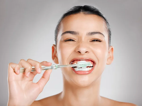 Niech dentysta będzie dumny. Studio ujęcie atrakcyjnej młodej kobiety myjącej zęby na szarym tle. — Zdjęcie stockowe
