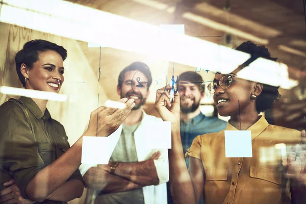 Hard werken staat gelijk aan succes. Schot van een groep zakenlui brainstormend met noten op een glazen muur. — Stockfoto