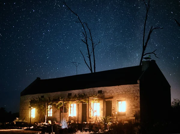 Sigue la luz todo el camino de regreso a casa. Fotografía de una casa en el campo en una oscura noche estrellada. — Foto de Stock
