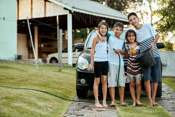 家族は常に一緒に働くべきです。一緒に立っている若い子供たちのグループの肖像画と日中に外で両親の車を洗うしようとしています. — ストック写真