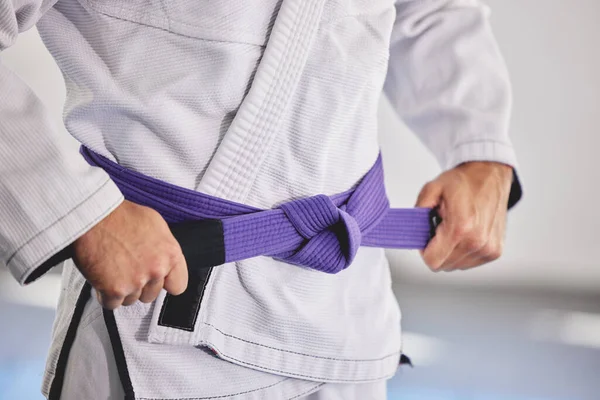 Připraven k boji. Vystřižený záběr na nepoznatelného muže, jak přivazuje fialový opasek kolem jejího pasu, zatímco v plné jiu jitsu gi. — Stock fotografie