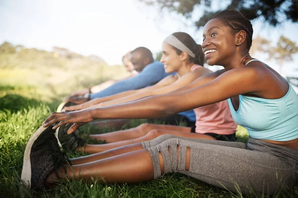 It feels good to make healthy choices. Shot of a fitness group stretching before their run. — Stock Photo, Image