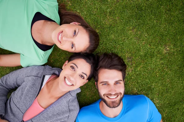 We always have a blast together. High angle shot of a three friends lying down on grass. — Stock Photo, Image