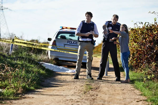 Prendo la sua dichiarazione. Colpo di pistola ad una donna che mostra agli agenti di polizia dove ha trovato il corpo in un crimescene. — Foto Stock